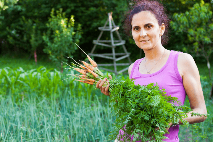 Mulher agricultora segurando cenouras